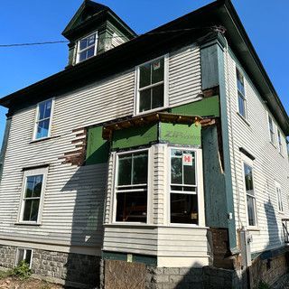 A white house with a green roof is being demolished.