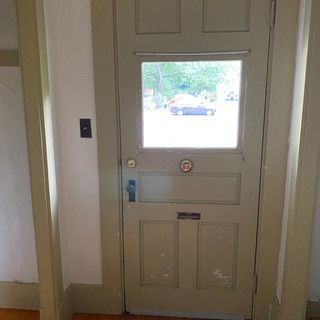 A door with a window in a room with a car in the background.
