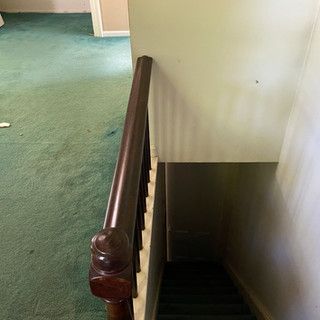 A staircase with a wooden railing and a green carpet.