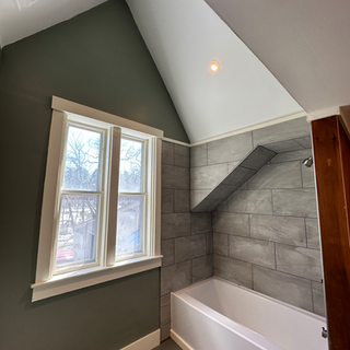 A bathroom with a bathtub and two windows