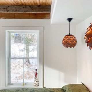 A bedroom with a bed , a window and a lamp hanging from the ceiling.