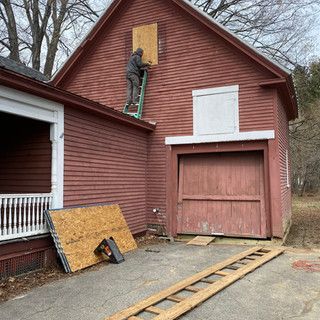 A man is standing on a ladder on the side of a house.