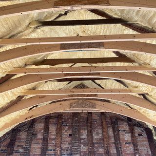 The ceiling of a building with wooden beams and foam on it.