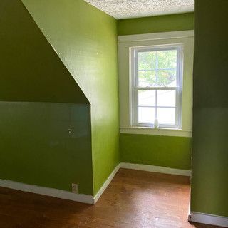 An empty room with green walls and a window.