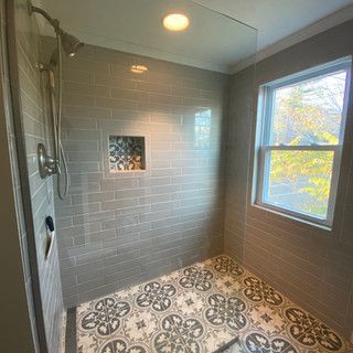 A bathroom with a walk in shower and a window.