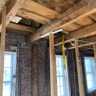 A room with brick walls and wooden beams and a yellow caution tape hanging from the ceiling.