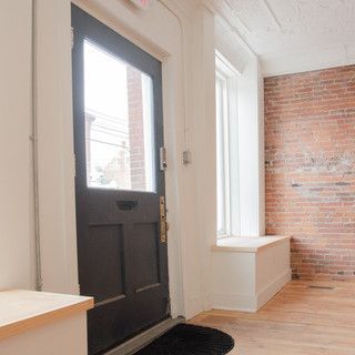 A hallway with a black door and a brick wall