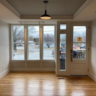An empty room with hardwood floors , a door , and a lot of windows.
