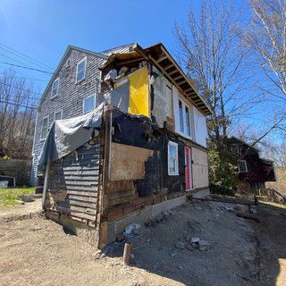 A small house is sitting on top of a dirt hill.