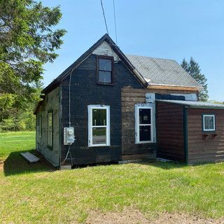A small house is sitting in the middle of a grassy field.