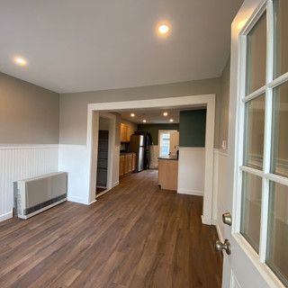 A living room with hardwood floors and a door leading to a kitchen.