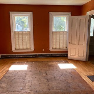 An empty living room with two windows and a door.