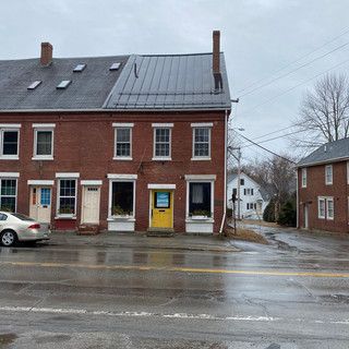 A brick building with a yellow door and a car parked in front of it.