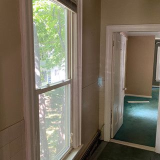 A hallway with a window and a door leading to a bedroom.