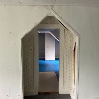 There is a doorway in the wall that leads to a room with a blue rug.