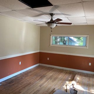 An empty room with a ceiling fan and a window.