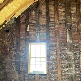 There is a window in the attic of a brick building.