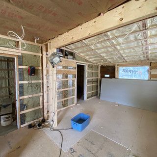 A room under construction with a blue bucket on the floor.