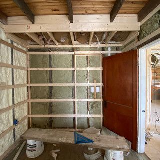 A room under construction with a wooden ceiling and a wooden door.