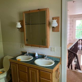 A bathroom with two sinks , a toilet and a mirror.