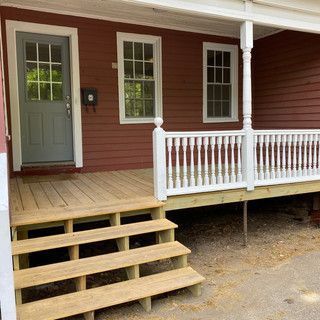 A red house with a wooden porch and white railing.