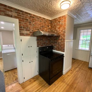 A kitchen with a black stove and a brick wall.