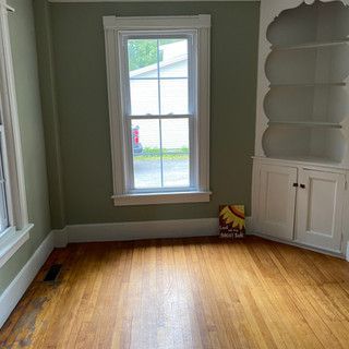 An empty room with hardwood floors and a window.