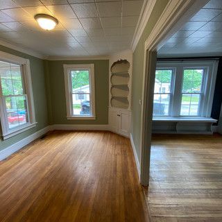 An empty living room with hardwood floors and green walls.