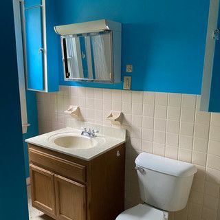 A bathroom with a sink , toilet , mirror and blue walls.