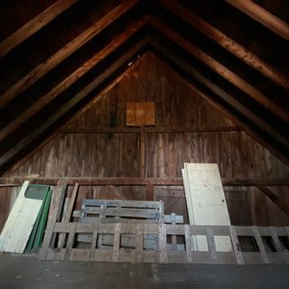 A wooden attic with a vaulted ceiling and a few pieces of wood on the floor