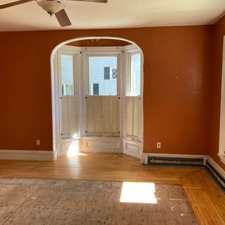 An empty living room with orange walls and a ceiling fan.