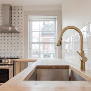 A kitchen with a sink , stove , and window.