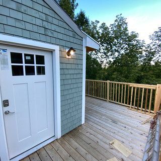 A white door is on the side of a house next to a wooden deck.
