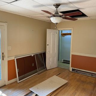 An empty room with a ceiling fan and a door.