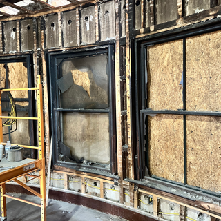 A scaffolding is sitting in front of a wall with broken windows