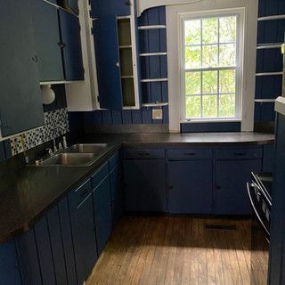 A kitchen with blue cabinets , a sink , and a window.