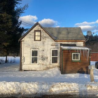 A small house in the snow with a satellite dish on the roof.