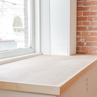A wooden window sill with a brick wall in the background.
