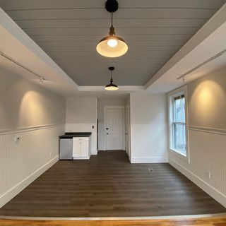 An empty living room with hardwood floors and a ceiling light.