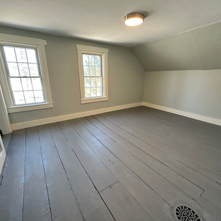 An empty room with a gray floor and two windows