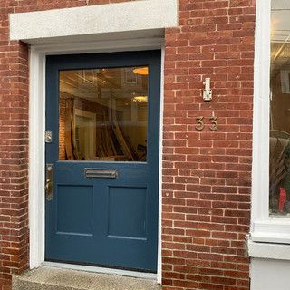 A blue door is on the side of a brick building.