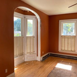 An empty room with orange walls and wooden floors.