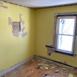 An empty room with yellow walls and a window.