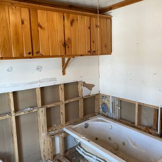 A bathroom with a bathtub and wooden cabinets.