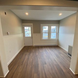 An empty living room with hardwood floors and a door.
