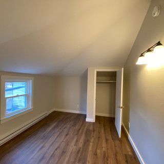 An empty room with hardwood floors , a window and a closet.