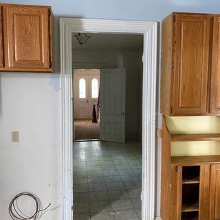 A kitchen with wooden cabinets and a door leading to a hallway.