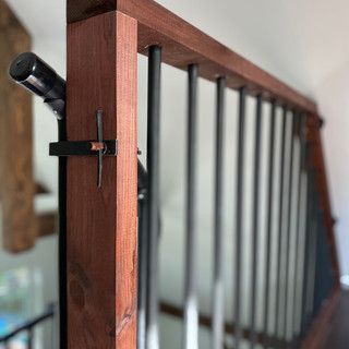 A close up of a wooden railing with metal bars on a staircase.