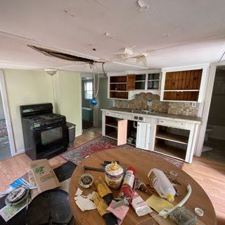 A kitchen with a broken ceiling and a table in the middle of the room.