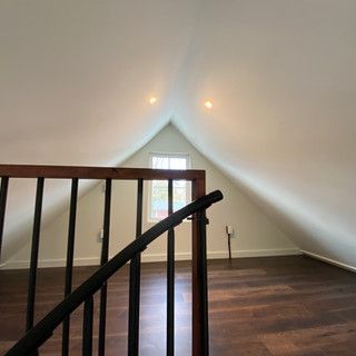An empty attic with a staircase and a window.
